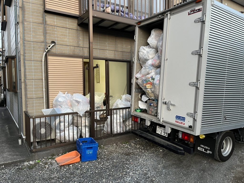 東京都板橋区のゴミ屋敷片付け，トラックいっぱいに積み込まれたゴミとベランダにまだ残っているゴミ